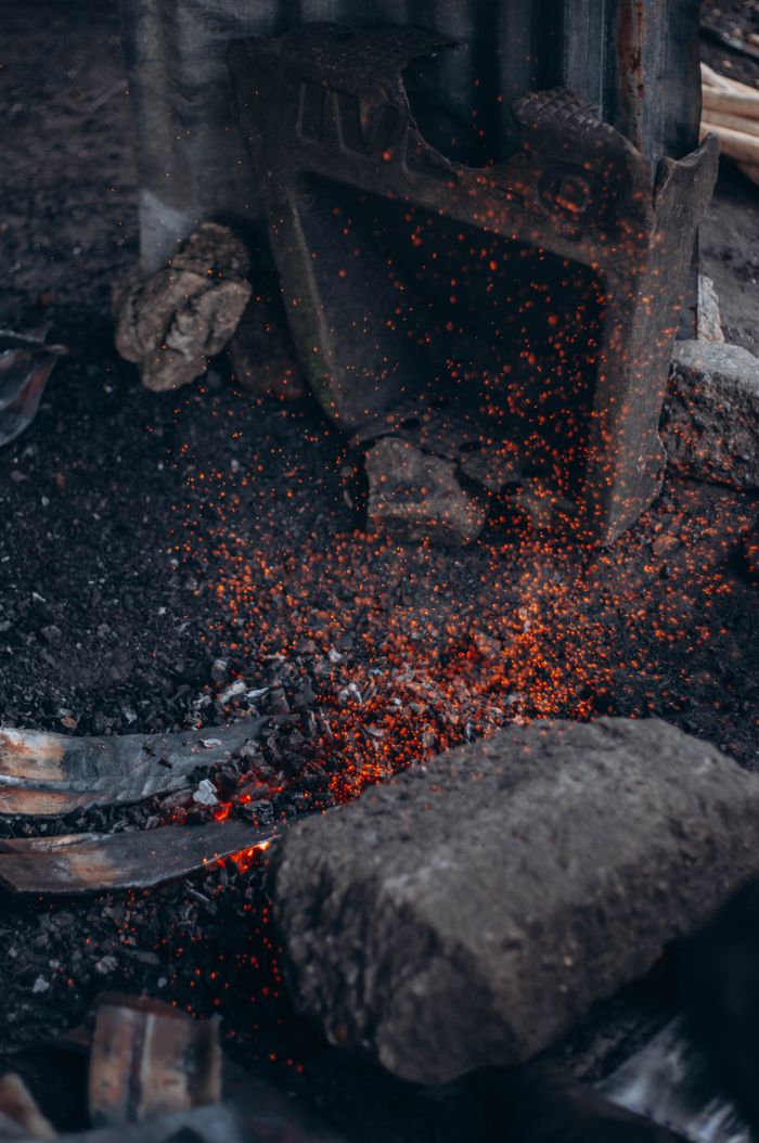 Captured glowing embers amid dark ashes in a rustic hearth, creating a moody ambience.